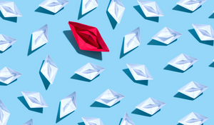 Unique big paper boat surrounded by many small paper boats