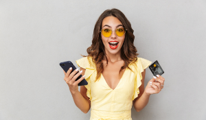 excited woman holding credit card and mobile phone