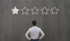 Man looking at one out of five stars on blackboard background