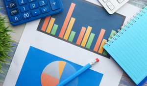 Graphs on table with notebook, pencil and calculator
