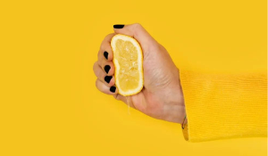 hand squeezing lemon on yellow background